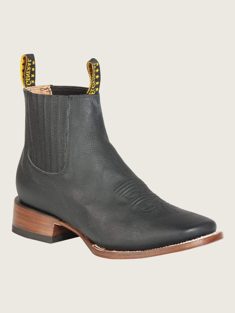Black leather Chelsea boot with brown sole on a light gray background