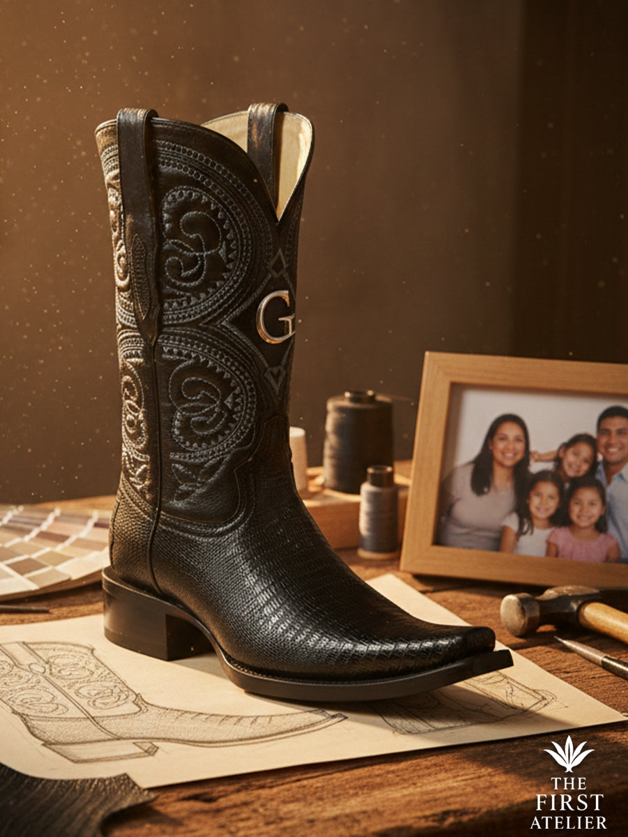 Finished black lizard leather western boot displayed on an atelier table with sketches and tools, highlighting fine scale texture and artisan finishing.
