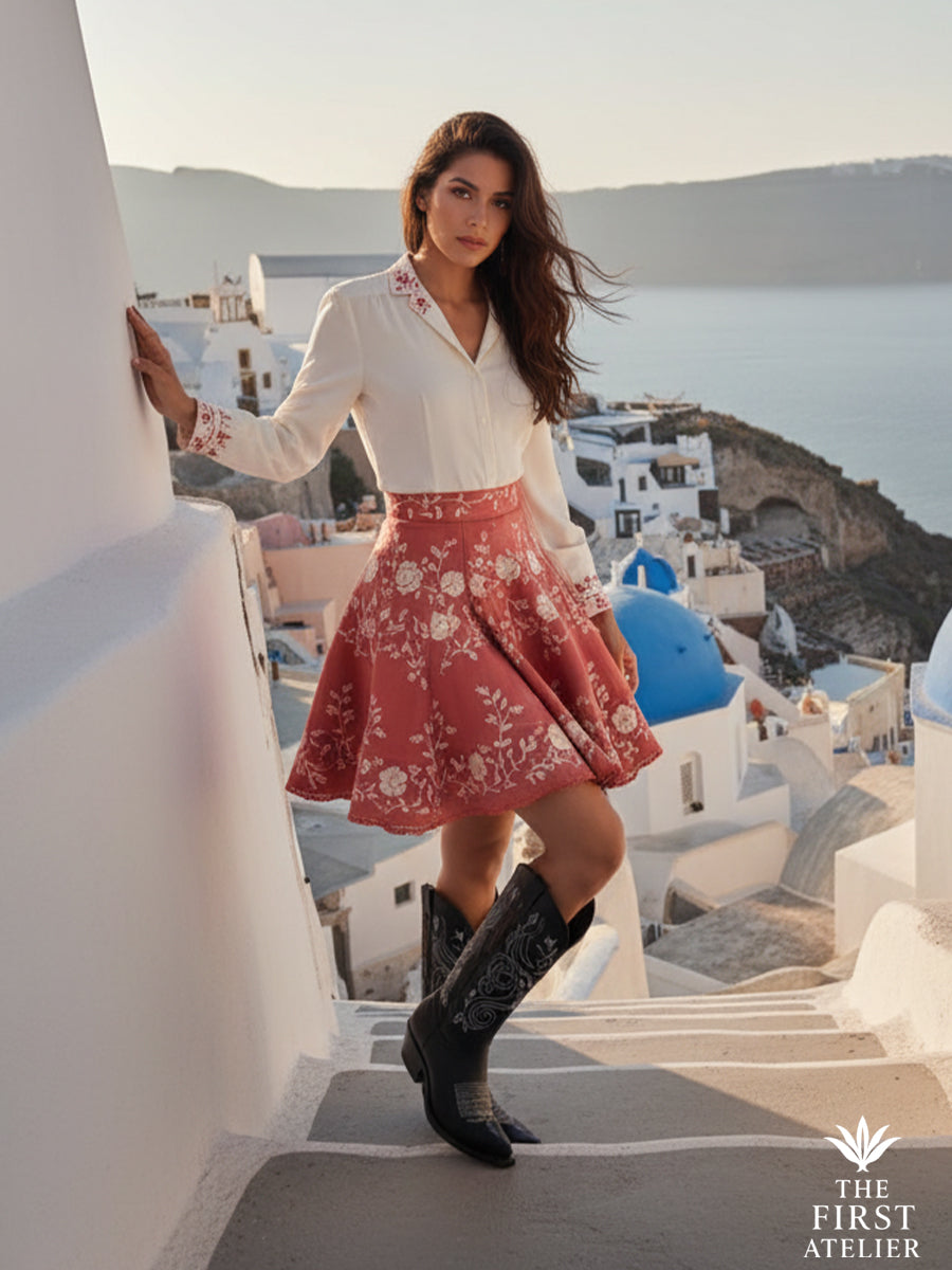 Model wearing the La Flor del Egeo Boot with a white blouse and coral skirt on Santorini’s sunlit steps — grace meets geometry.
