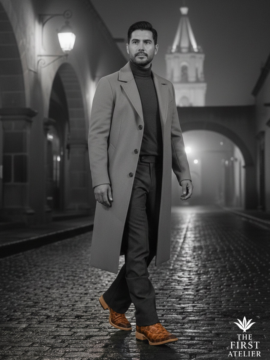 Black-and-white editorial portrait of a man wearing a men’s western boot crafted in ochre pirarucu leather, expressing quiet strength and timeless presence through a refined western silhouette, The First Atelier, Atelier No. 34.
