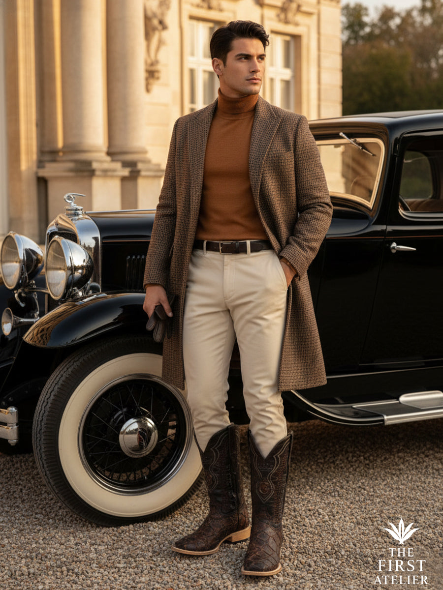 Man standing beside a classic automobile wearing the El Terreno Boot in dark textured leather, styled with tailored trousers and knitwear, expressing timeless masculine elegance and grounded presence, The First Atelier, Atelier No. 35.
