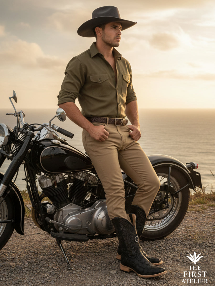Man beside a classic motorcycle near the coast wearing the El Tránsito Boot crafted in black pirarucu (monster fish) leather, capturing movement, freedom, and modern western elegance in transit, The First Atelier, Atelier No. 36.
