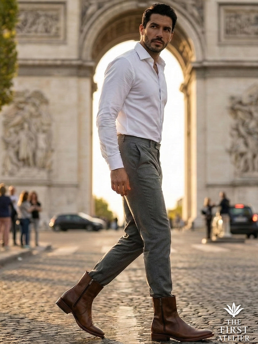 Man walking near the Arc de Triomphe wearing Atelier No. 71 El Destino Boot, showcasing sophisticated urban style and cognac leather.