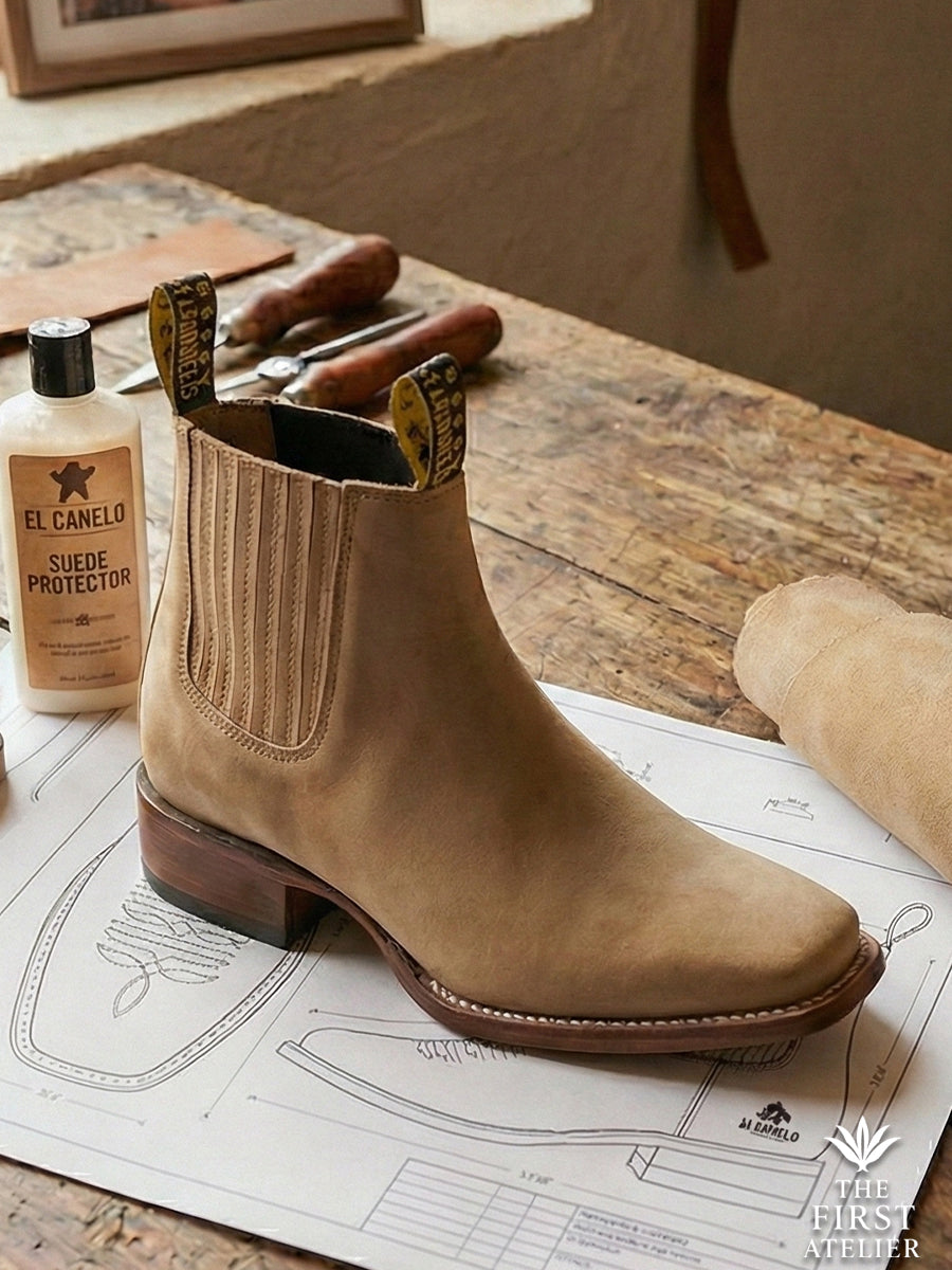 Studio display of the Atelier No. 73 El Sendero Boot in tan suede alongside leather care tools, highlighting the square toe silhouette.