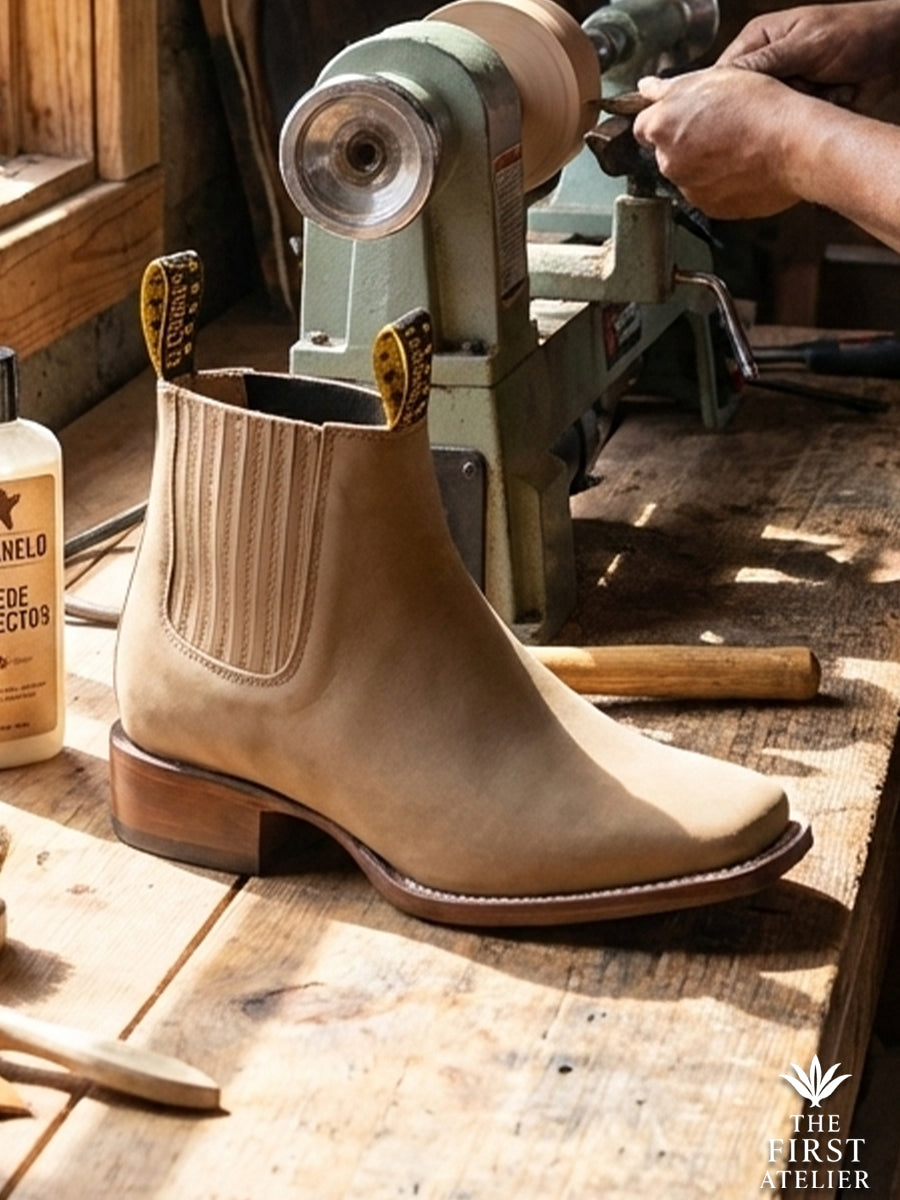 Close-up of Atelier No. 73 El Sendero Boot in premium tan suede, featuring a distinct square toe and handcrafted hardwood heel on the workbench.