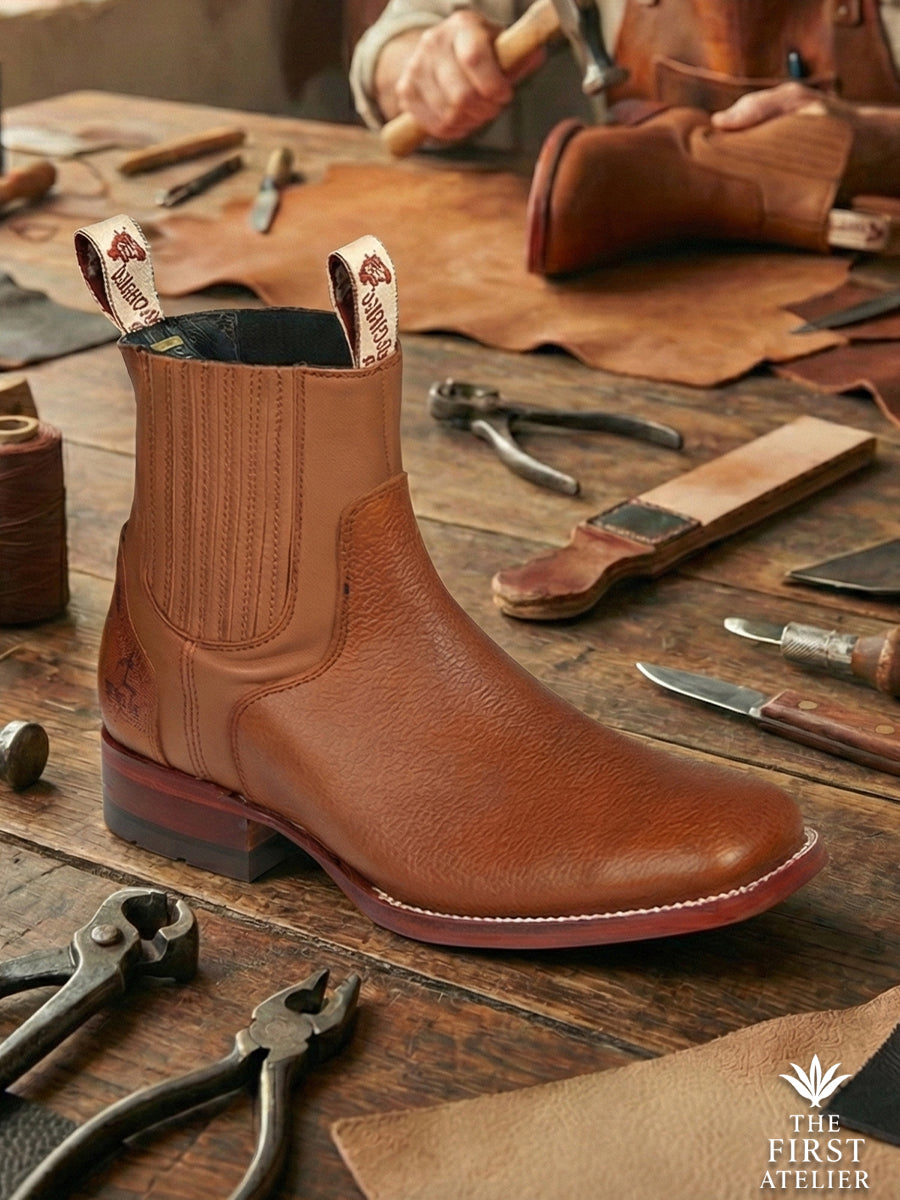 Close-up of Atelier No. 77 El Atlas Boot showing the rich pebbled texture of the cognac leather and the signature cherry-finish heel stack.