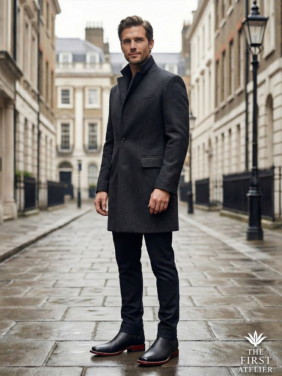 Gentleman sitting on a concrete seawall with a city bay background, wearing the versatile black textured Atelier No. 79 boot.