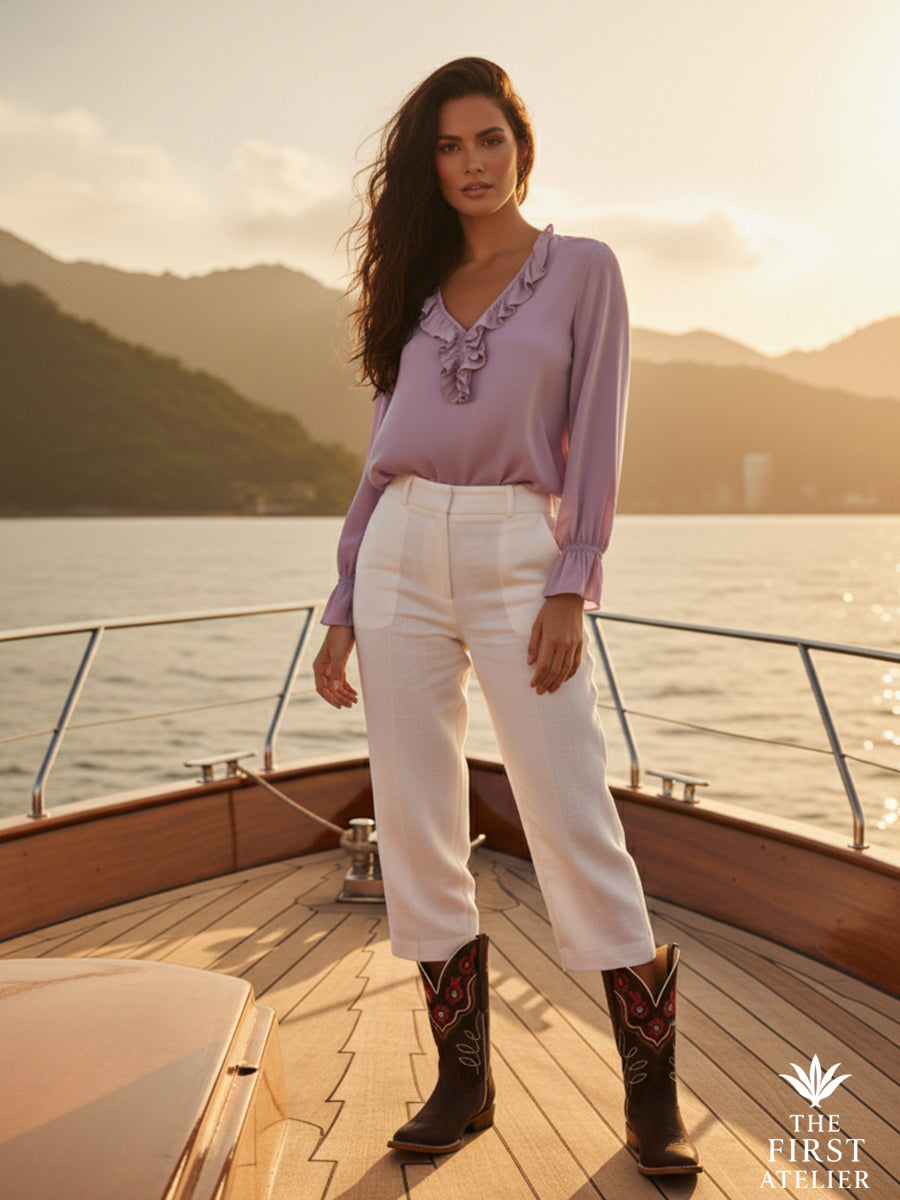 Woman standing aboard a wooden boat in soft evening light, wearing The Atelier Mirador Boot — calm confidence on the water.
