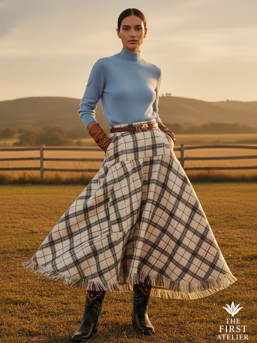 Woman in a long plaid skirt on an open field at dusk, wearing Atelier No. 26 — La Rosa del Invierno boots.