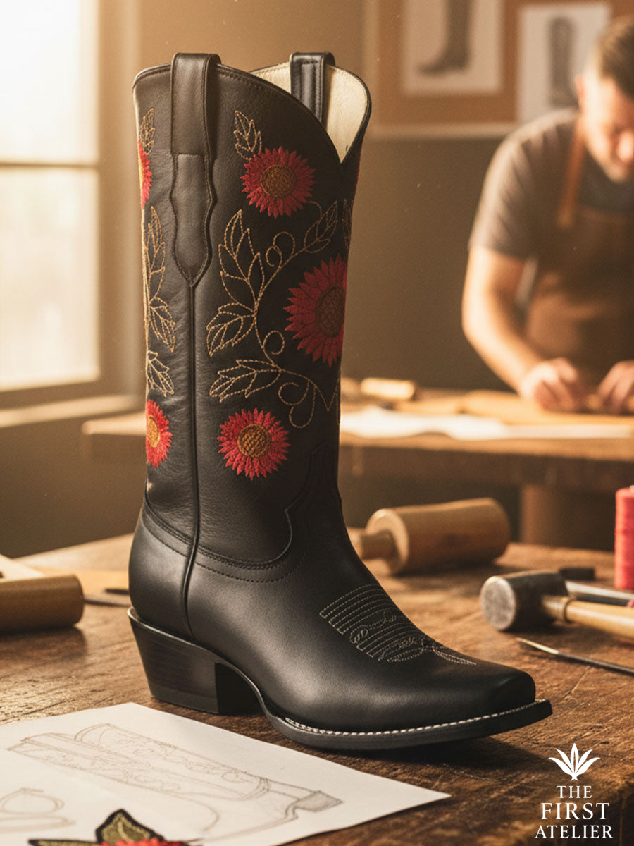 Close-up of La Flor del Sol Boot — black leather with fiery sunflower embroidery in gold and red tones, handcrafted in León, Guanajuato, Atelier No. 7.
