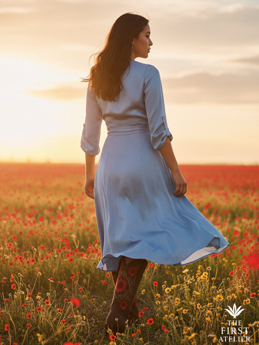 Woman walking through a field at sunset wearing La Flor de la Vida Boot — brown leather with red floral embroidery — a symbol of vitality and elegance, Atelier No. 8.