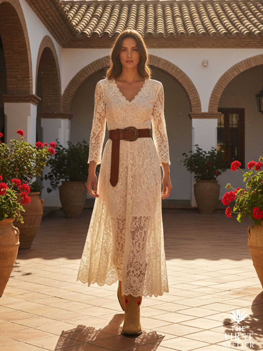 Woman walking through a Mexican courtyard in a cream lace dress and La Flor del Alba Boot — tan leather boots with red embroidery, handcrafted in León, Guanajuato.