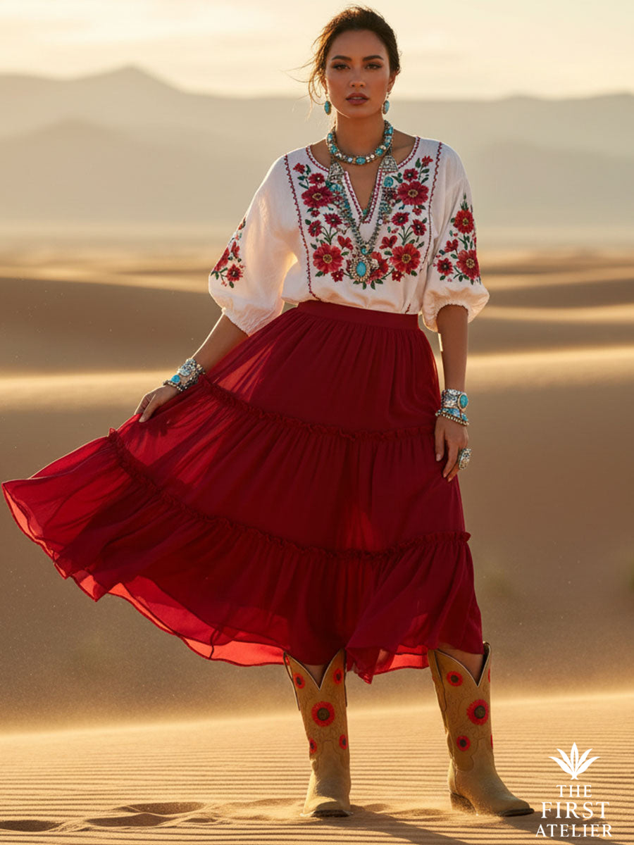 Woman in flowing red skirt standing in desert light wearing La Flor del Alba Boot — tan leather cowboy boots with vivid red floral embroidery, Atelier No. 10