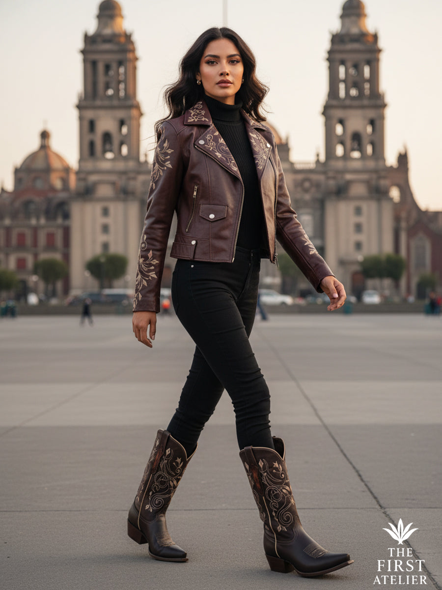 Woman walking through a historic city plaza wearing the La Senda Firme Boot in deep brown leather, highlighting a tall embroidered western silhouette in motion, Atelier No. 32.
