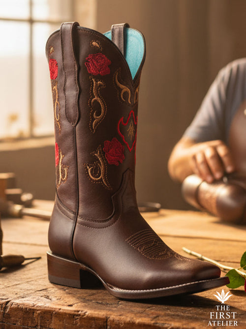 Close-up of the Rosewood Whisper Boot showcasing handcrafted rosewood leather and crimson-gold floral embroidery under soft artisan light, Atelier No. 01.