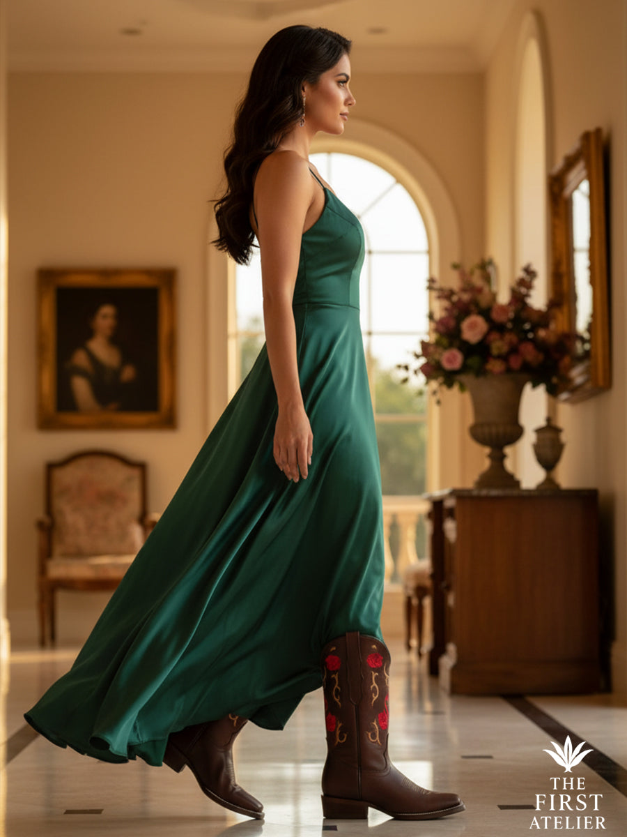 Editorial full-body shot of a woman in an emerald silk dress walking gracefully while wearing the Rosewood Whisper Boot, highlighting its artisan craftsmanship.